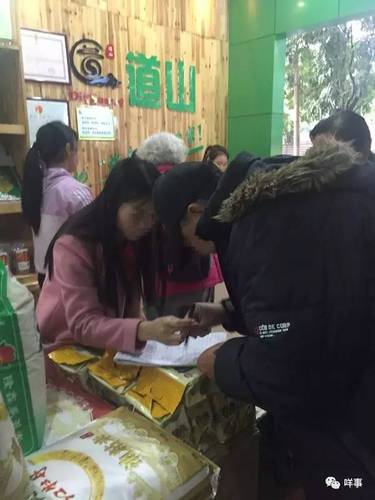 值班的业务员正为一名老人登记会员资料并派发团购券。