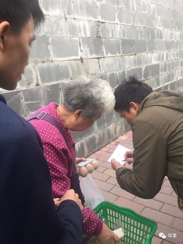 有老人上前询问，经理上前登记派发团购券。