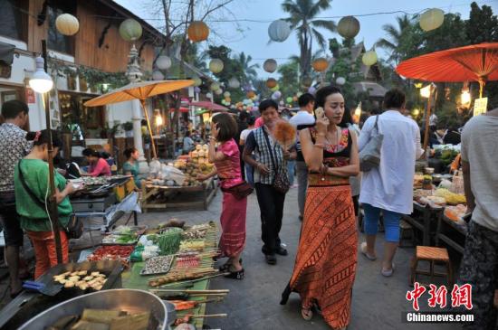 4月13日，云南西双版纳“告庄西双景”内，逛夜市的游客?！案孀魉啊蔽鲇?，意为“九塔十二寨”，位于澜沧江畔，占地1200亩的景区内傣式风格浓郁。自2012年开业至今，年接待游客量已经突破400万人次，2015年春节期间，日均游客人数突破10万人次，成为云南旅游新地标。 <a target='_blank' href='http://www.chinanews.com/'>中新社</a>记者 任东 摄
