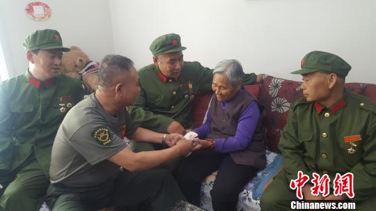 图为老兵们将慰问金送到门二柱母亲手中。　吕新颖 摄