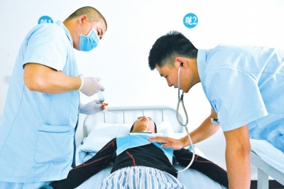 一名护士给病人喂食，另一名监测病人的身体状况。