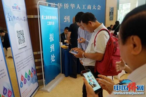第二届华侨华人工商大会报到现场，中国新闻社“侨宝”客户端及中国侨网微信宣传品吸引了高度关注，嘉宾纷纷扫码下载。付强 摄