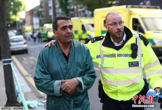 当地时间6月14日凌晨，伦敦西部一栋20余层的公寓大楼发生大火，火势猛烈，几乎蔓延到了所有楼层。约200名消防员和40辆消防车前往灭火。图为警方协助被疏散民众（左）撤离。