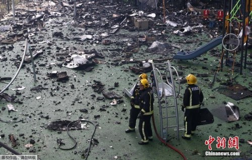 图为消防员在瓦砾中行进。