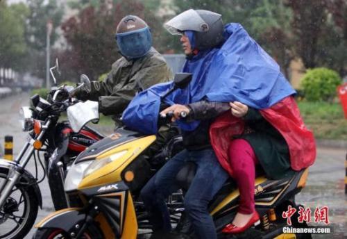 资料图：民众在雨中出行。