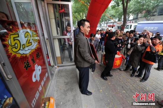 10月11日，在山西太原5.2亿元人民币福彩大奖诞生投注站，站主杨文生收到当地福彩中心发放的奖励后，引来周围民众的围观。10月5日晚，中国福利彩票双色球游戏第14115期开奖，当期双色球头奖开107注，单注奖金为520.68万元，其中山西独揽101注，奖金高达5.2亿，是中国彩票史上第三大奖。一时间，“买彩票中大奖”成为当地民众坊间热议的话题，5.2亿福彩大奖诞生投注站也成彩民争相前往的“景点”。中新社发 韦亮 摄