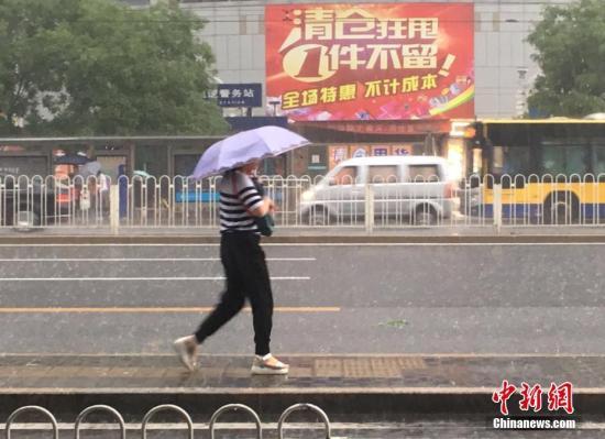 6月23日清晨，北京市民冒雨出行。 中新网记者 富宇 摄