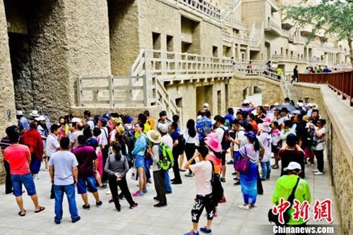 资料图：敦煌莫高窟窟区“游人如潮”。王斌银 摄