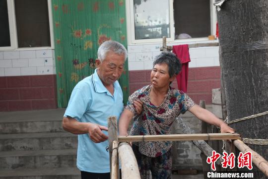 为让妻子慢慢学会走路，李文生每天扶着妻子一遍一遍练习走路?！±钤汉?摄