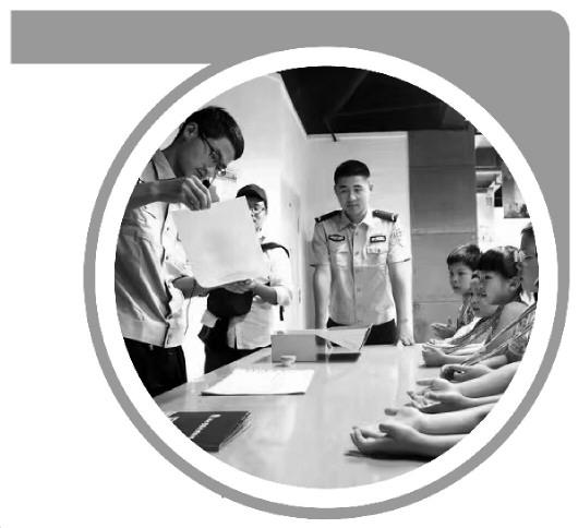 图2为2017年5月20日“彩虹亲子营”活动，湖北警察史博物馆讲解员刘泽恩（左一）为小朋友们讲解指纹按捺。