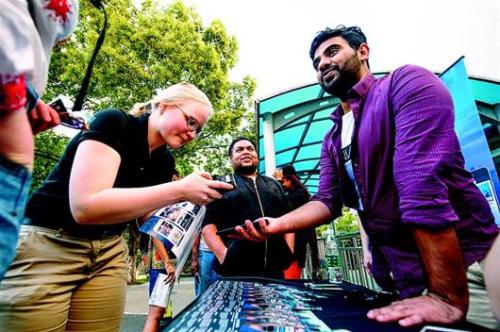 图为HanNation的团队成员塞舍尔(右)在校园里向留学生推介他们的APP。