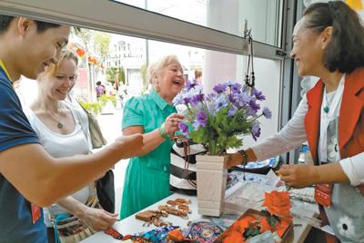 在莫斯科的北京地坛庙会上，北京民间工艺美术大师、绢花工艺传承人徐汶静(右一)带来的传统绢花颇受欢迎。本报记者 吴 焰摄