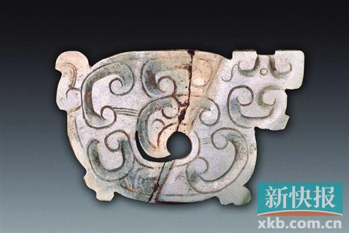 玉龙形饰 春秋 青绿色，薄片体。为长方形，身体卷曲，头侧视，圆形小眼，吻部前伸，下部似有双足，另一侧有一弯尾。一面饰勾云纹，中部身躯镂空成涡形孔，器物表面有切割痕。另一面光素无纹。春秋时期琢玉技艺有了很大的进步，制出了更为精美的玉器，纹饰从平面向隐起、从简单到繁复的方向发展，雕刻技法采用浮雕、镂空与阴刻相结合。