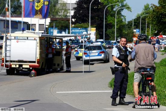 一名警察在案发现场附近与一个骑自行车的路人交谈。