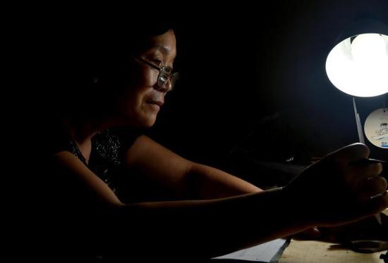 王从苗在自己的卧室内认真观察陶片。新华社发 （李嘉南 摄）