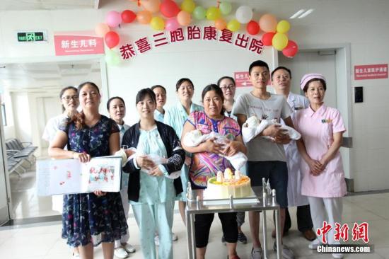 图为医护人员和三胞胎及家人合影。 钟欣 摄
