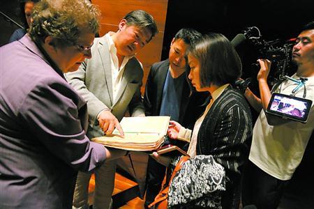 中国侨网克里斯缇娜（左一）介绍纪念册内容。 蔡磊磊　摄