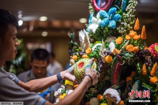 资料图：一名泰国男子用雕刻的水果和蔬菜拼成一件精心制作的装饰品。