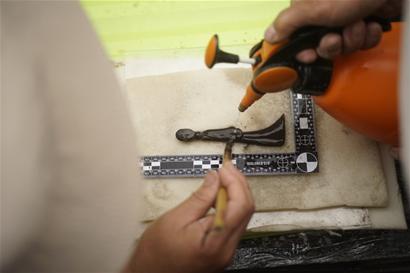 考古队员在清理出土的器物