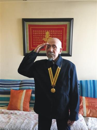 去年初，关爱抗战老兵组织为董老颁发纪念章，他起身敬礼致谢。图片来源：新京报