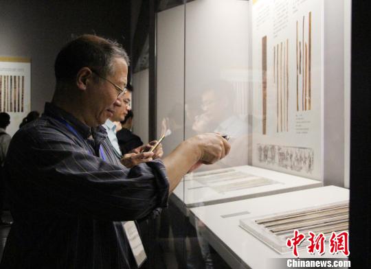 图为参展观众在中国简帛文化展上观看和拍摄简帛文物?！≌韵∩? longdesc=