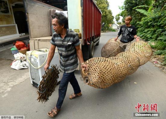 当地时间9月21日，印尼巴厘岛阿贡火山周围地壳运动大幅度加强，印尼地质局已将其警戒级别提升至第三级，该警戒级别表示火山两星期内存在喷发的可能性。图为当地居民携带物品离开危险区域。
