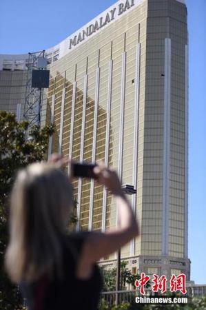 当地时间10月4日上午，美国拉斯维加斯曼德勒海湾酒店门前道路解除封锁、恢复行人和车辆通行，只是在酒店正门口仍有黄色警戒线、警车和全副武装的警察。金碧辉煌的酒店外墙上，两个黑洞洞的破损窗口触目惊心。10月1日晚，一名枪手正是砸破了这两处窗户，向不远处举行露天乡村音乐节的人群扫射，夺去50多人生命，造成美国现代历史上伤亡最惨重的枪击事件。很多当地民众和外国游客4日来到这里，举着手机拍下这两个“夺命窗口”。 <a target='_blank' href='http://www.chinanews.com/'>中新社</a>记者 张朔 摄