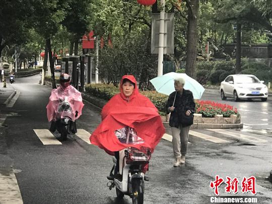 11日，南京迎来降温降雨。图为市民披上雨衣出行?！⊙钛沾?摄