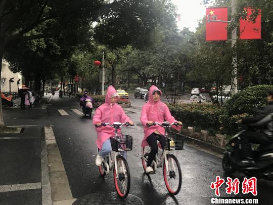 11日，南京迎来降温降雨。图为市民披上雨衣出行?！⊙钛沾?摄