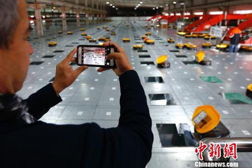 图为在申通物流公司内，记者在拍摄智能机器人自动分检系统的工作实况。　富田 摄