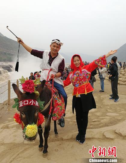 缅甸南坎明德学校的负责人杨蜜蜜与弟弟杨彪在黄河岸边穿上极具地方特色的服饰，骑着毛驴合影留念?！⊙罱苡?摄