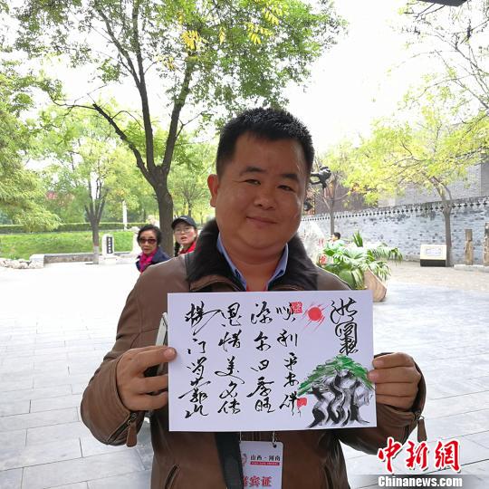 缅甸大其力大华学校负责人杨恩源在洪洞大槐树景区向记者展示自己姓氏的文创产品?！⊙罱苡?摄