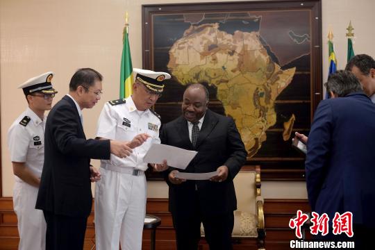当地时间10月5日，在加蓬总统府，“和谐使命—2017”任务指挥员管柏林向加蓬总统邦戈赠送2009年中加“和平天使”联合演习中邦戈总统的资料照片?！〗?摄