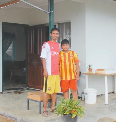 塔诺阿莱客索诺·阿莱克斯和儿子在新房前合影。 　　本报记者 颜 欢摄