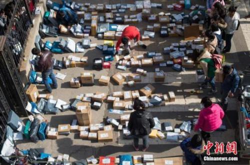 随着2016年“双十一”网购落幕，中国各地迎来快递派送高峰。图为工作人员忙着分拣满地的快递。武俊杰 摄
