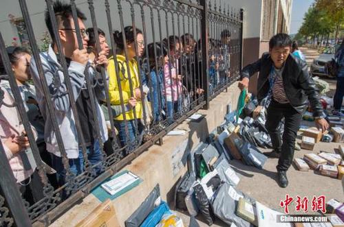 10月8日，山西太原，山西财经大学校园外一处空地上摆满各个物流公司发来的快递，众多学生隔着栅栏排队等候收取。国庆节后高?？兹沼次锪鞲叻澹挂恢艿难何锲芳蟹址?，现场一片忙碌。武俊杰 摄