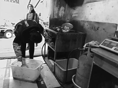 店老板在调整煤气灶的火苗。