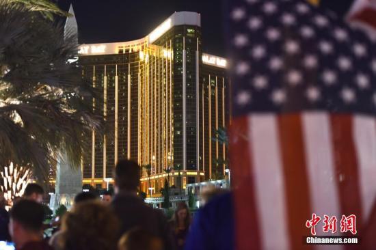 当地时间10月3日晚，很多人聚集在美国拉斯维加斯市中心曼德勒海湾酒店附近，悬挂起一面美国国旗，用烛光和鲜花吊唁10月1日晚那场严重枪击事件中的遇难者。 <a target='_blank' href='http://www.chinanews.com/'>中新社</a>记者 张朔 摄