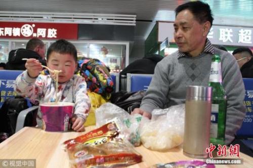 资料图：春运途中，有旅客喝着小酒就花生。图片来源：视觉中国