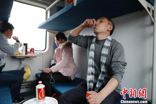 48岁的张师傅喝着朋友送的酒，和儿子和儿媳妇一起回云南昭通老家过年。　殷立勤 摄