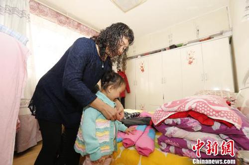 图为彭秀芳妈妈为玲玲穿新衣。　胡贵龙 摄