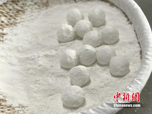 "制作元宵时，首先要将馅料做好，沾上水，再投进盛满糯米粉的笸箩内摇。<a