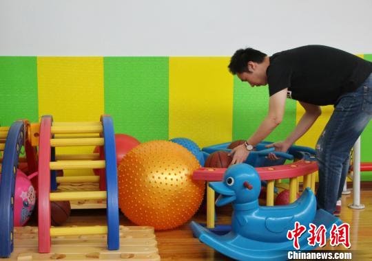 图为自闭症康复教师正在收拾整理自闭症孩子日常锻炼所使用的器具?！≌韵?摄