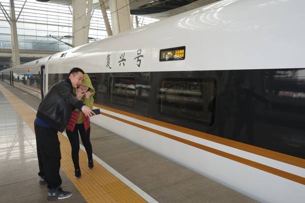 一对情侣在“复兴号”高铁前自拍