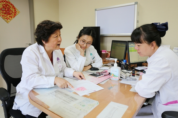 廖秦平在门诊中和医生一起讨论病例。杨欣 摄