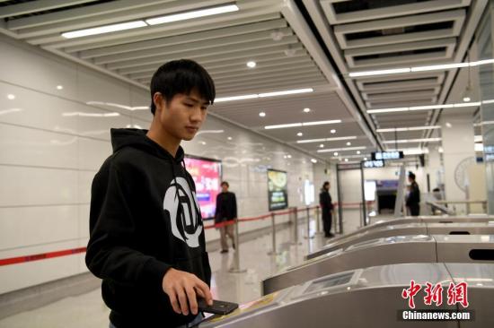 12月28日，一名乘客使用蓝牙感应通过地铁闸机。当日，南宁地铁2号线开通试运营，同时全线开启手机感应过闸服务，市民下载APP后，打开蓝牙，即可感应通关。 <a target='_blank' href='http://www.chinanews.com/'>中新社</a>记者 俞靖 摄