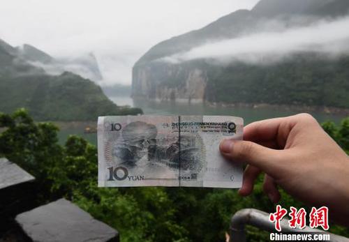 图为游客在人民币十元背景图实景地驻足参观，并拍照留念。　周毅　摄