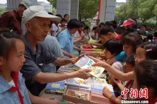 周火生和志愿者们通过书籍义卖筹集捐助款。周火生希望爱心接力可以不断延续下去?！∽柿贤计?摄