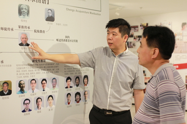 程凯（左）为参观展览的领导、专家介绍程莘农院士学术思想传承体系