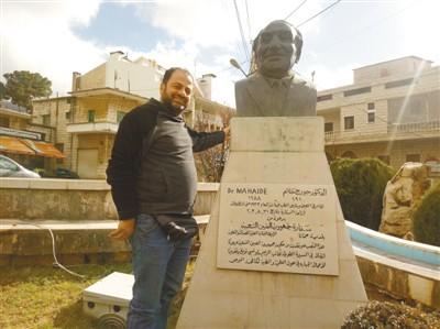 中国侨网当地居民与位于哈马纳小镇的马海德雕像合影。 　　本报记者 黄培昭摄